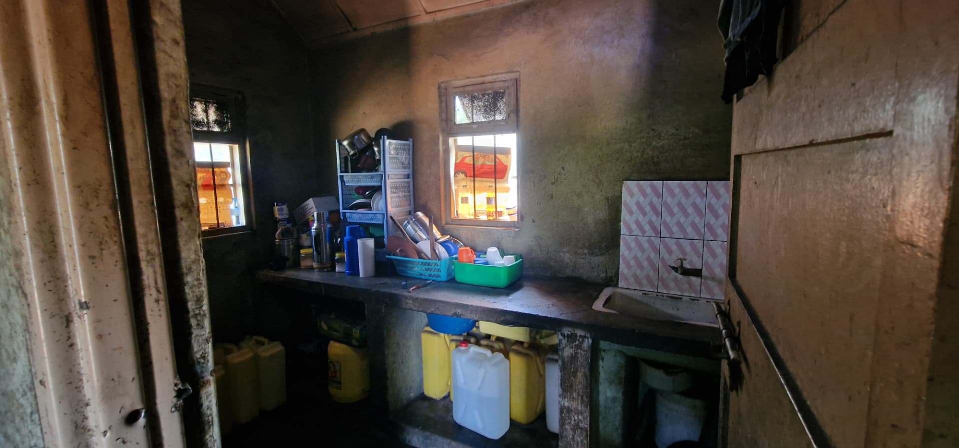 Interior kitchen with concrete counter, sink, dishes and water containers