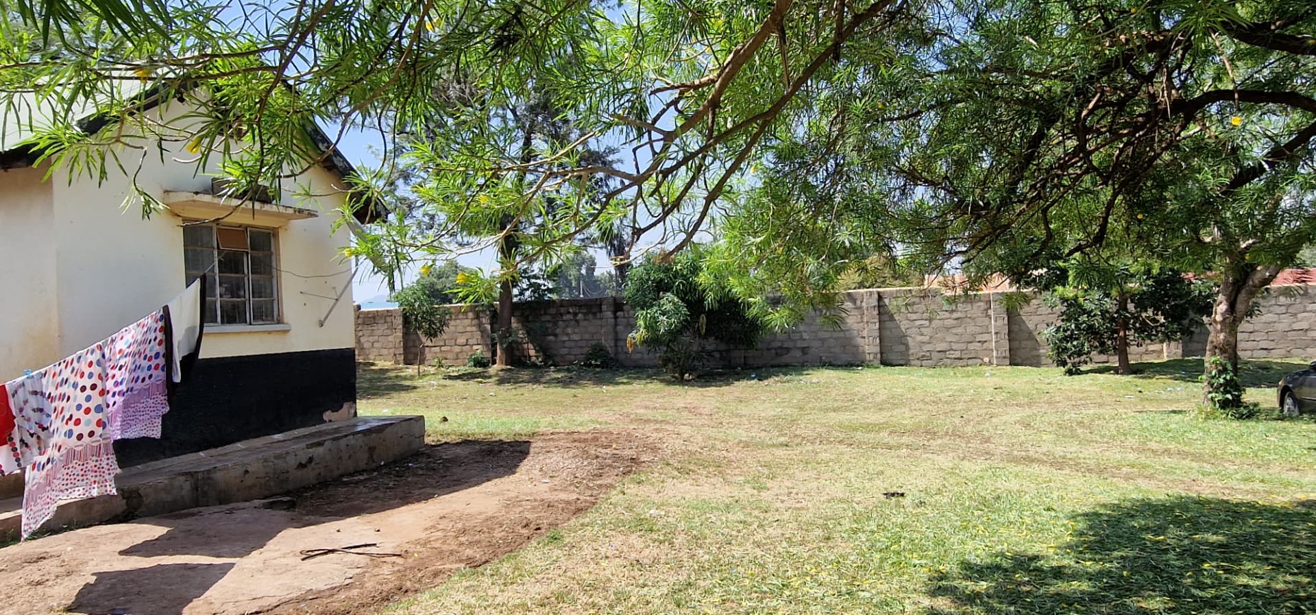Open grass yard beside the house enclosed by a stone block wall