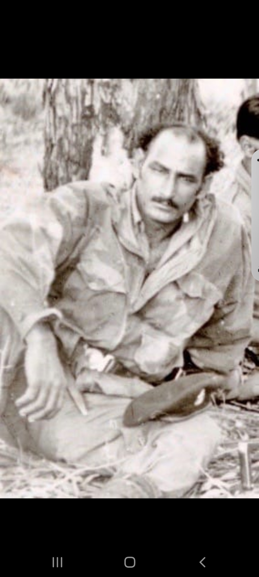 Dada Abu resting under a tree in the field with a colleague