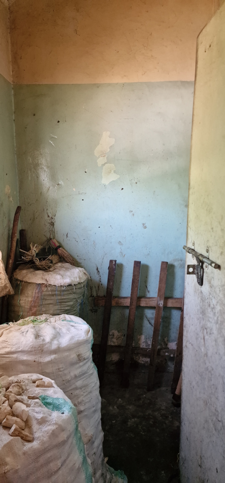 Store room interior with sacks, hand tools and a wooden frame against a painted wall