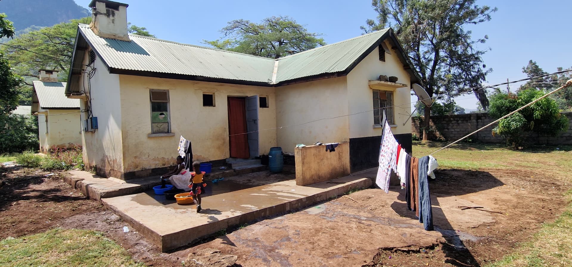 Courtyard side of the house with a red curtained doorway, washing lines and children