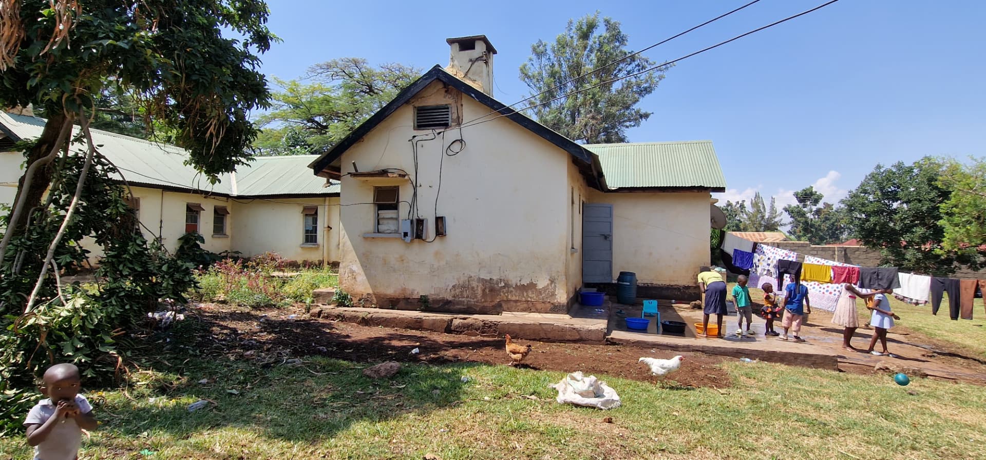 Side of the house with children, chickens and washing lines in the yard