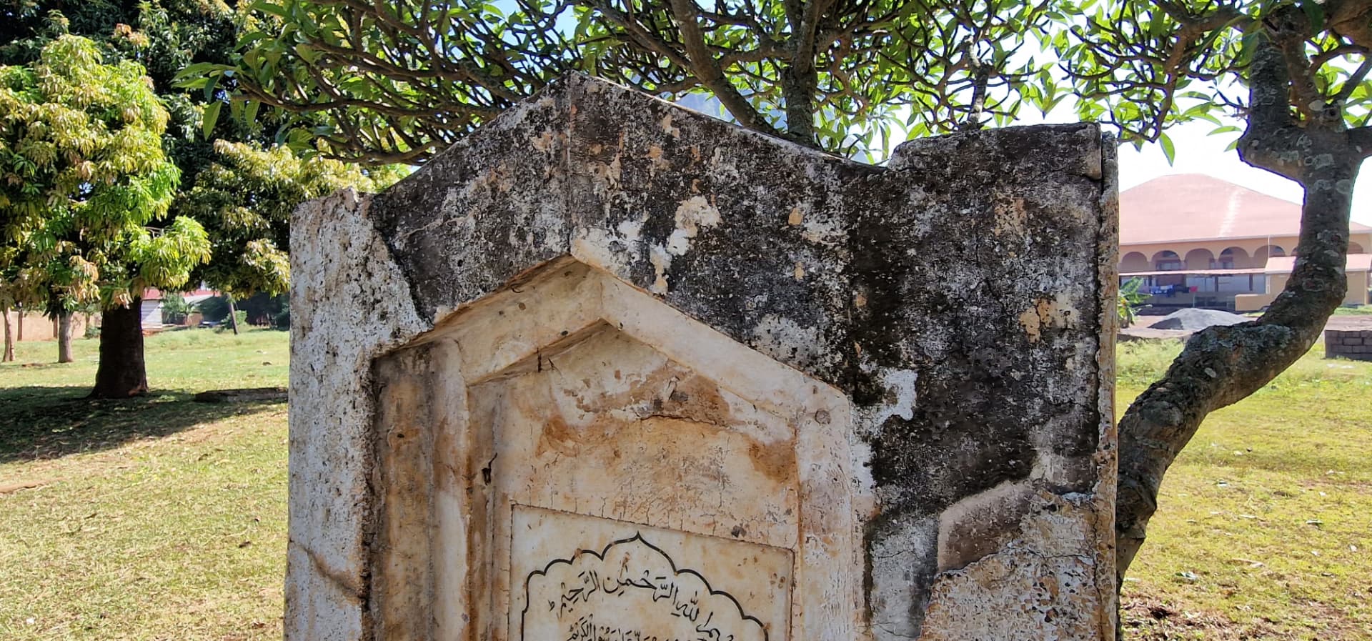 Close view of the weathered headstone and its arched surround