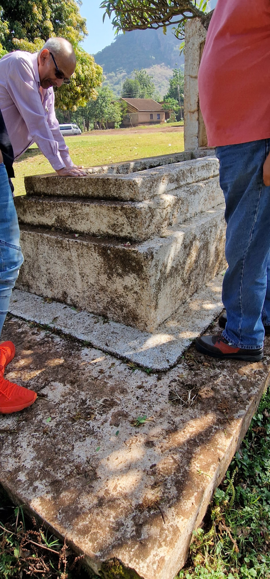 Family members standing at the tomb, one resting a hand on the stone